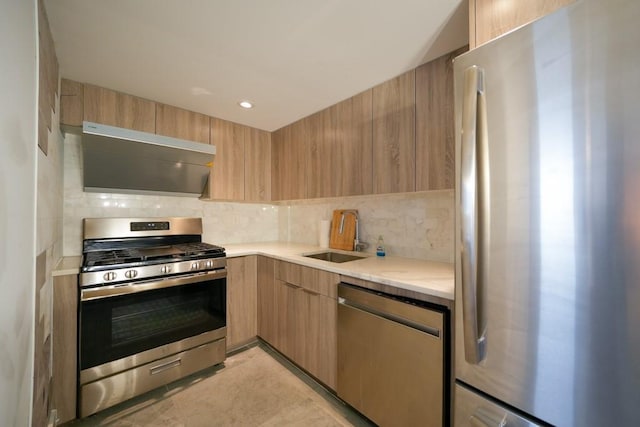 kitchen featuring modern cabinets, a sink, tasteful backsplash, appliances with stainless steel finishes, and wall chimney range hood