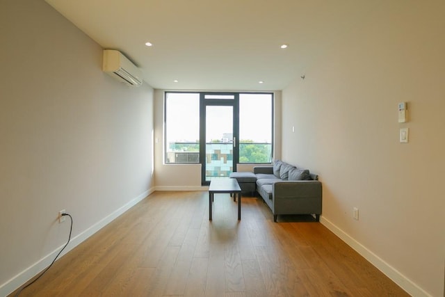 living area featuring baseboards, a wall unit AC, expansive windows, recessed lighting, and light wood-style flooring