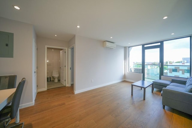 living room with an AC wall unit, electric panel, wood finished floors, and baseboards