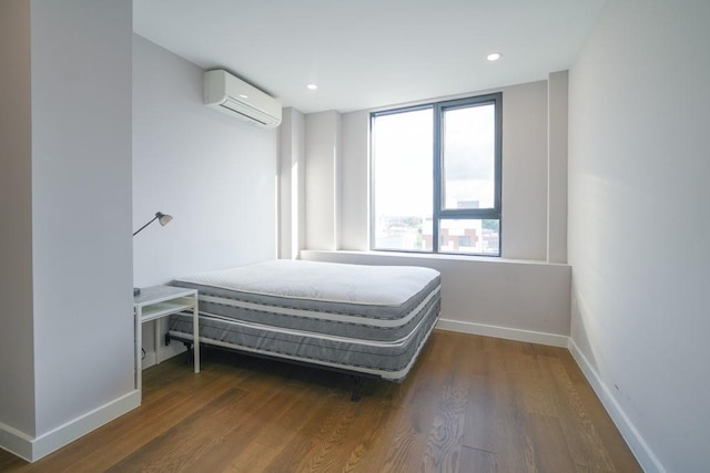 bedroom with recessed lighting, a wall mounted air conditioner, baseboards, and wood finished floors