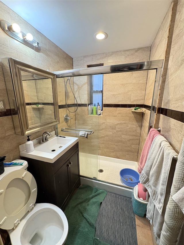 full bathroom featuring tile patterned flooring, a shower stall, toilet, vanity, and tile walls