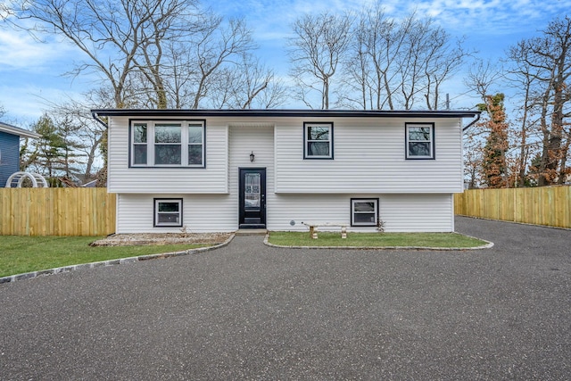 split foyer home featuring aphalt driveway and fence