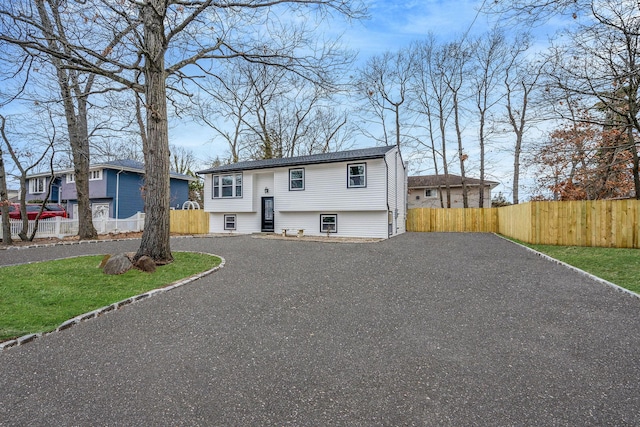 raised ranch with gravel driveway and fence