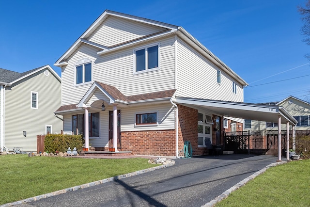 view of front of house with a front yard, a carport, brick siding, and aphalt driveway