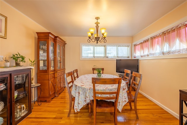 dining space with light wood finished floors, a chandelier, and baseboards