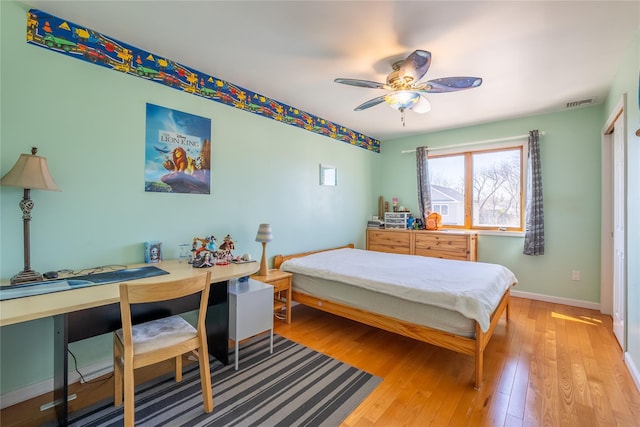 bedroom with light wood finished floors, visible vents, a ceiling fan, and baseboards