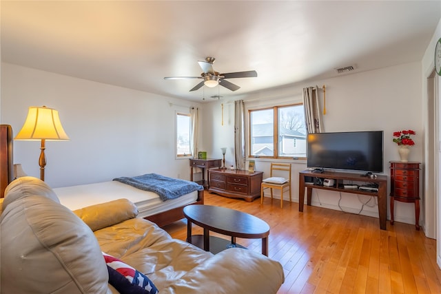 living room featuring light wood-style flooring, visible vents, and ceiling fan