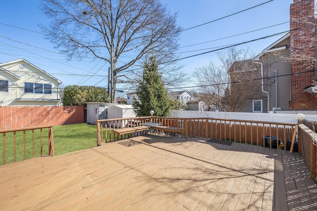 wooden terrace featuring a yard, a fenced backyard, a storage shed, and an outdoor structure