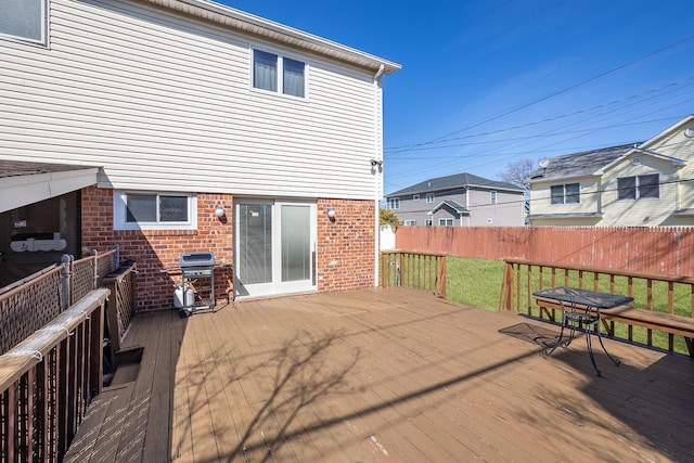 wooden terrace featuring a lawn, a grill, and fence