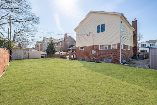 rear view of house with a storage unit, brick siding, a fenced backyard, and an outdoor structure