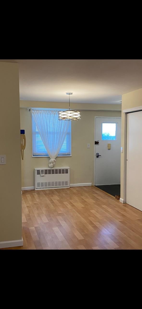 interior space with an inviting chandelier, radiator, and light wood finished floors