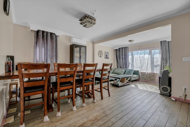 dining area with crown molding, a wall mounted AC, and wood finished floors