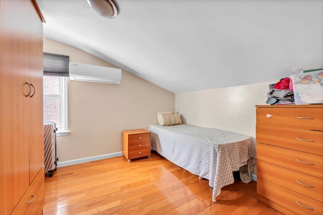 bedroom featuring lofted ceiling, baseboards, light wood-type flooring, and a wall mounted AC