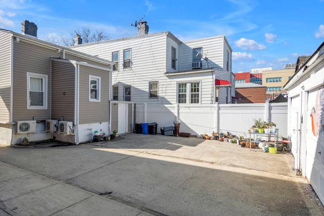 rear view of property featuring ac unit and fence