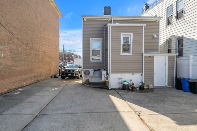 exterior space with concrete driveway, a chimney, and fence