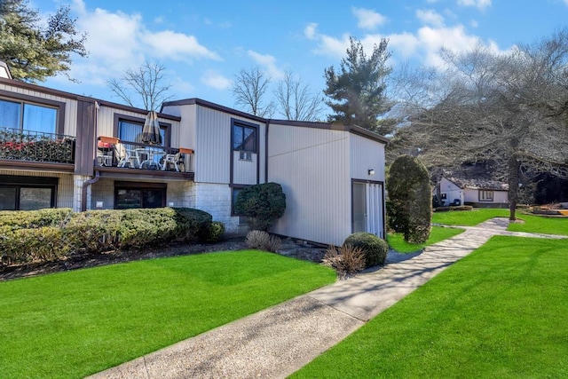 exterior space with a balcony, a lawn, and stone siding