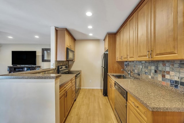 kitchen with baseboards, light wood-style flooring, recessed lighting, a sink, and black appliances