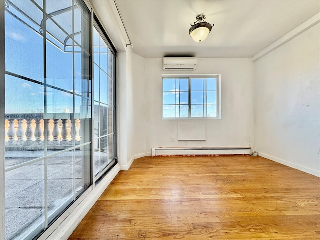 spare room with a baseboard heating unit, wood finished floors, baseboards, and a wall mounted AC