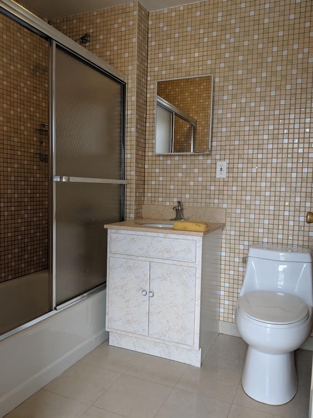 bathroom with tile patterned flooring, toilet, tile walls, and enclosed tub / shower combo