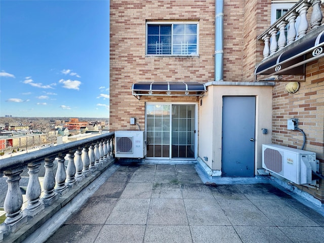 view of exterior entry featuring ac unit and brick siding