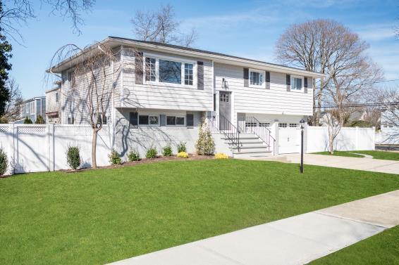 split foyer home with a front lawn, fence, a garage, and driveway