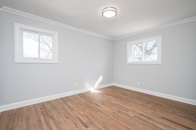 spare room featuring crown molding, baseboards, and wood finished floors