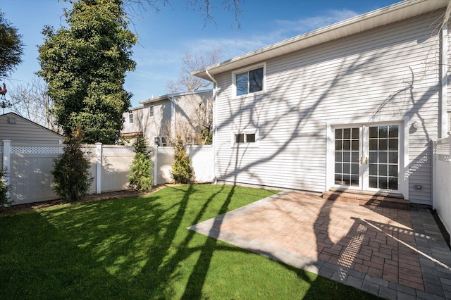 back of property with a patio, french doors, a yard, and fence