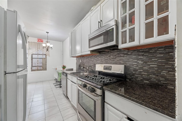 kitchen with tasteful backsplash, glass insert cabinets, appliances with stainless steel finishes, white cabinets, and a sink