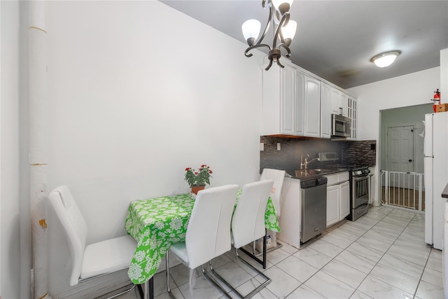 kitchen featuring a sink, appliances with stainless steel finishes, white cabinetry, dark countertops, and tasteful backsplash