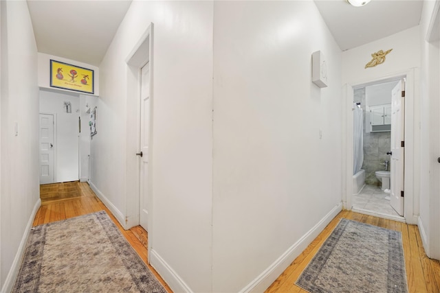 hallway featuring light wood-type flooring and baseboards