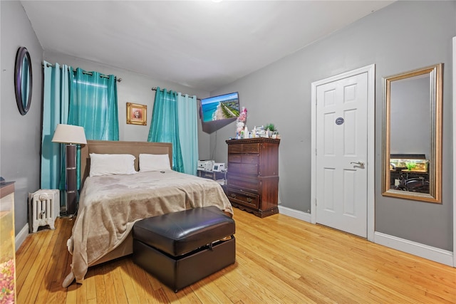 bedroom featuring baseboards, hardwood / wood-style floors, and radiator heating unit