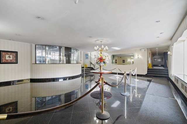 unfurnished dining area featuring granite finish floor, an inviting chandelier, wallpapered walls, and baseboards