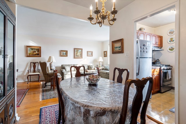 dining space featuring baseboards, light wood-style floors, and an inviting chandelier