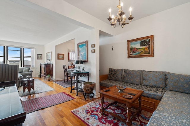 living room with baseboards, wood-type flooring, and an inviting chandelier