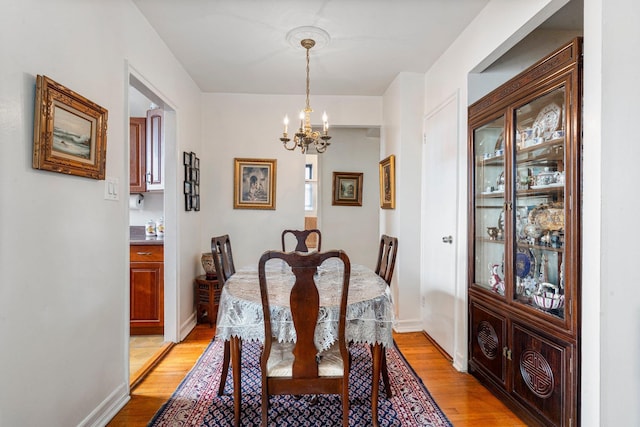 dining space with light wood-style floors, baseboards, and a chandelier