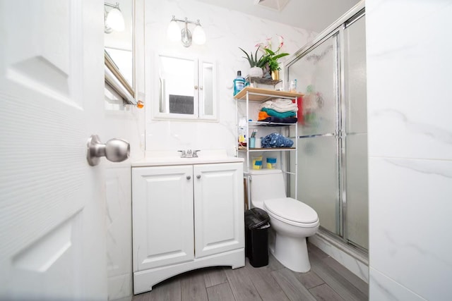 full bathroom featuring a stall shower, toilet, vanity, and wood tiled floor