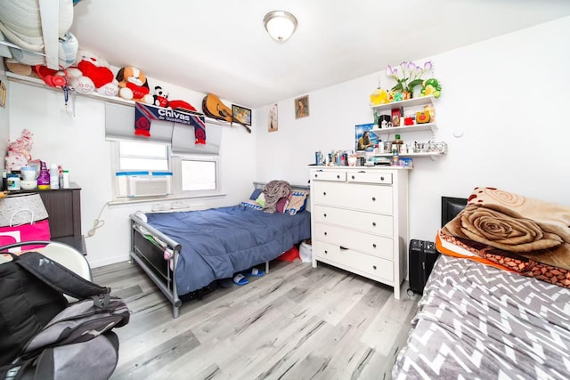 bedroom featuring cooling unit and light wood finished floors