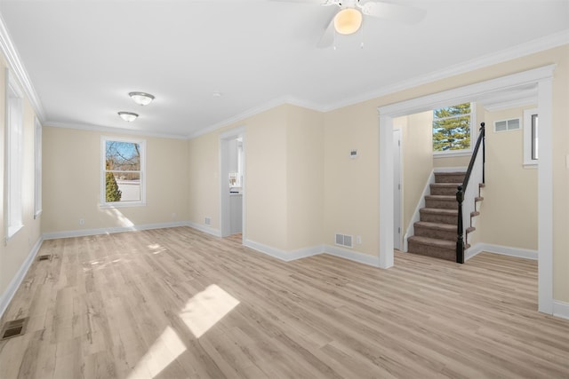 empty room featuring visible vents, stairway, light wood-style floors, and ornamental molding