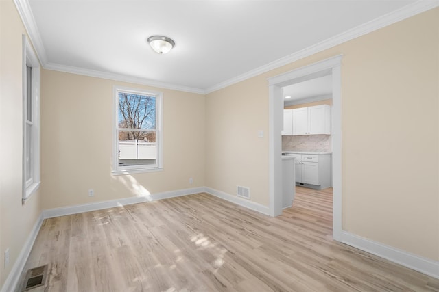 spare room with visible vents, baseboards, light wood-style floors, and crown molding