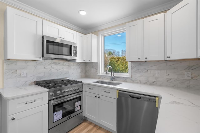 kitchen with tasteful backsplash, white cabinets, appliances with stainless steel finishes, and a sink