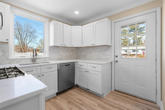 kitchen with ornamental molding, a sink, light wood-style floors, appliances with stainless steel finishes, and white cabinets