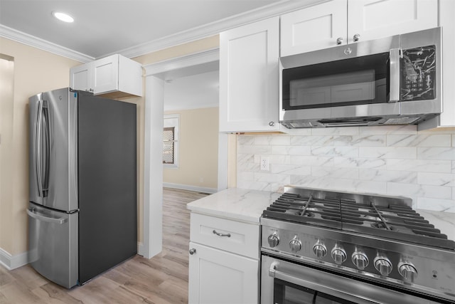 kitchen with light stone counters, white cabinets, stainless steel appliances, and crown molding