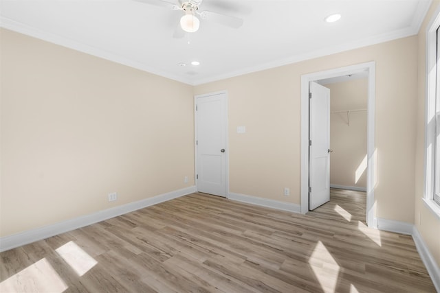 unfurnished bedroom featuring light wood finished floors, a spacious closet, baseboards, ornamental molding, and a closet