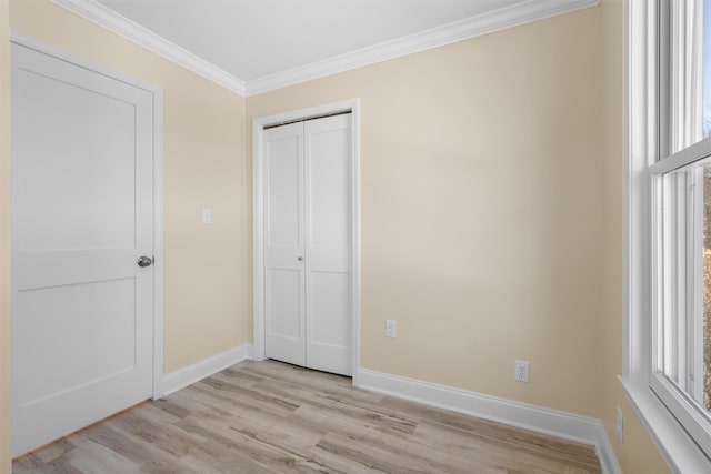 unfurnished bedroom with light wood finished floors, a closet, crown molding, and baseboards