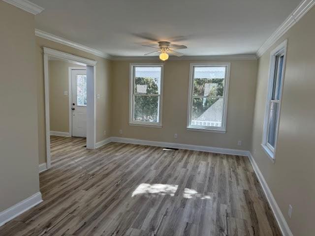 interior space featuring baseboards, a ceiling fan, wood finished floors, and crown molding