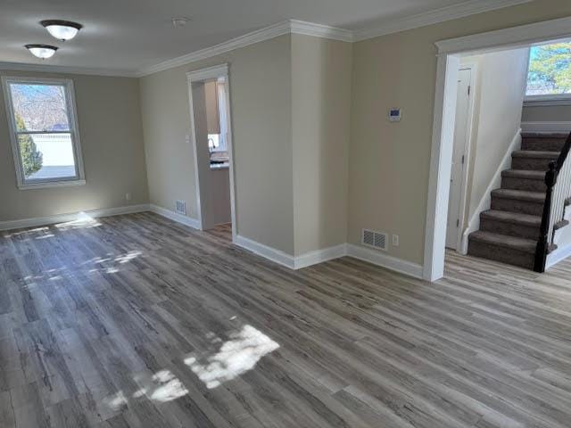 unfurnished room featuring visible vents, baseboards, stairs, ornamental molding, and wood finished floors