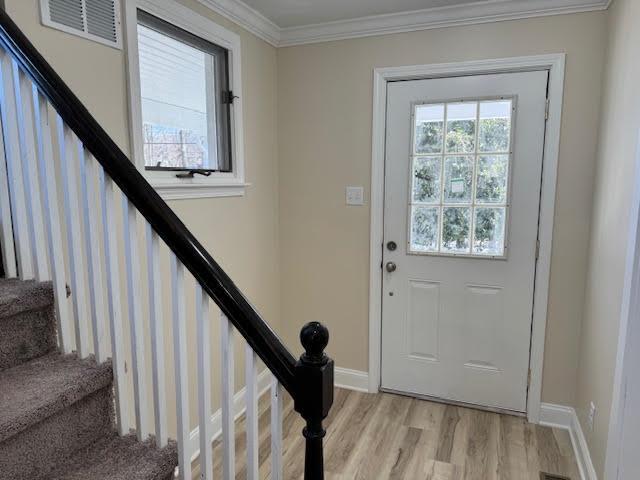 entryway featuring crown molding, stairway, visible vents, and light wood finished floors