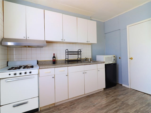 kitchen with white appliances, wood finished floors, ornamental molding, decorative backsplash, and under cabinet range hood