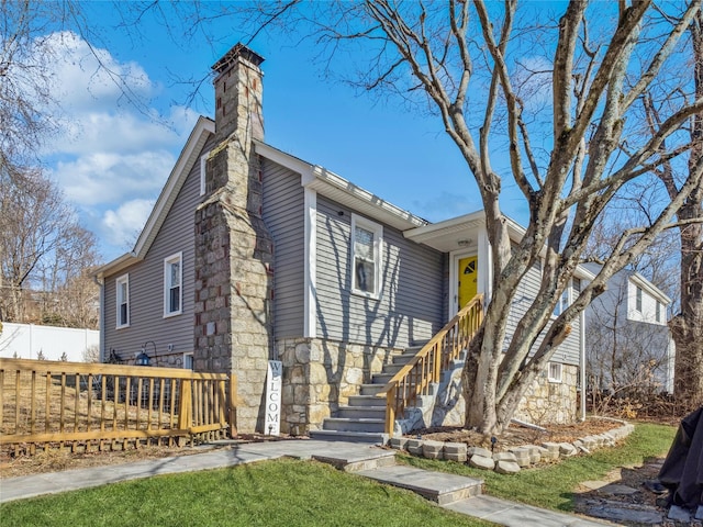 view of front facade with stairway, fence, a chimney, stone siding, and aphalt driveway