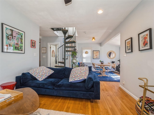 living room with baseboards, stairs, and light wood-style floors